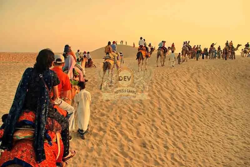 Line of camels and riders crossing the dunes