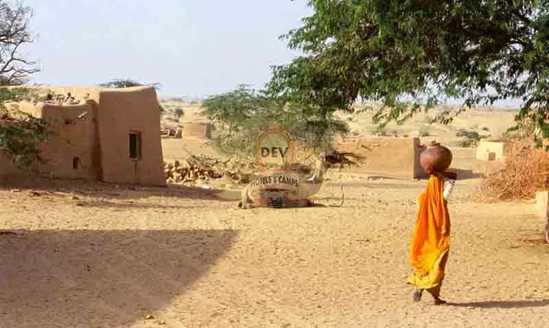 Villager walking past a mud house