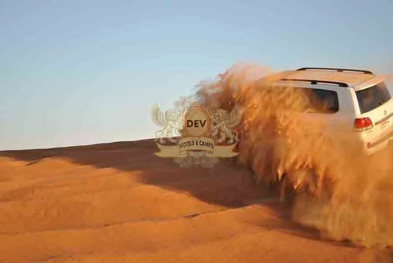 4x4 spraying sand over a dune crest