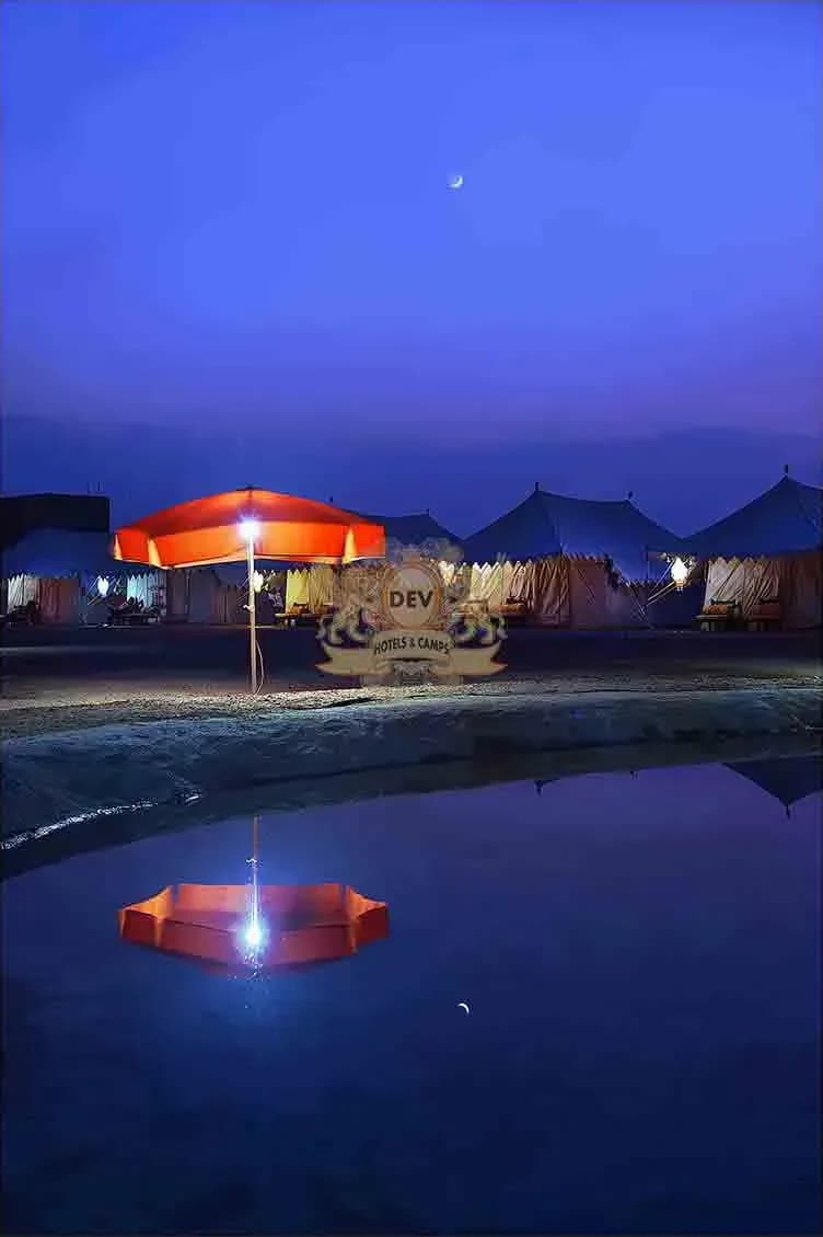 Camp e Khas tents and pond-side umbrellas lit up at blue hour
