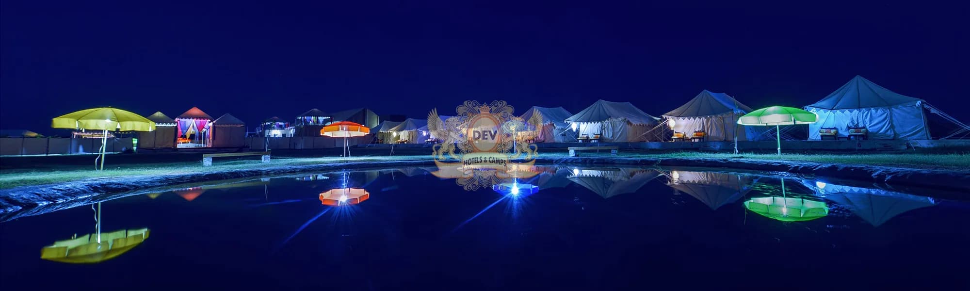 Camp e Khas lit up at night, reflected in the Talai pond