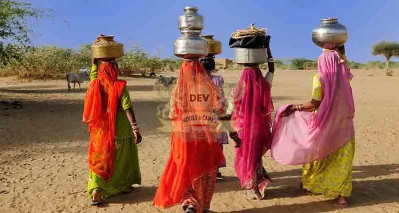 Women carrying water pots in a desert village